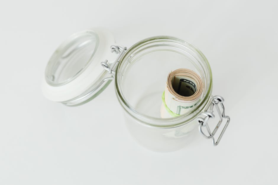 Close-up shot of rolled US dollar bills inside a glass jar on a white surface.