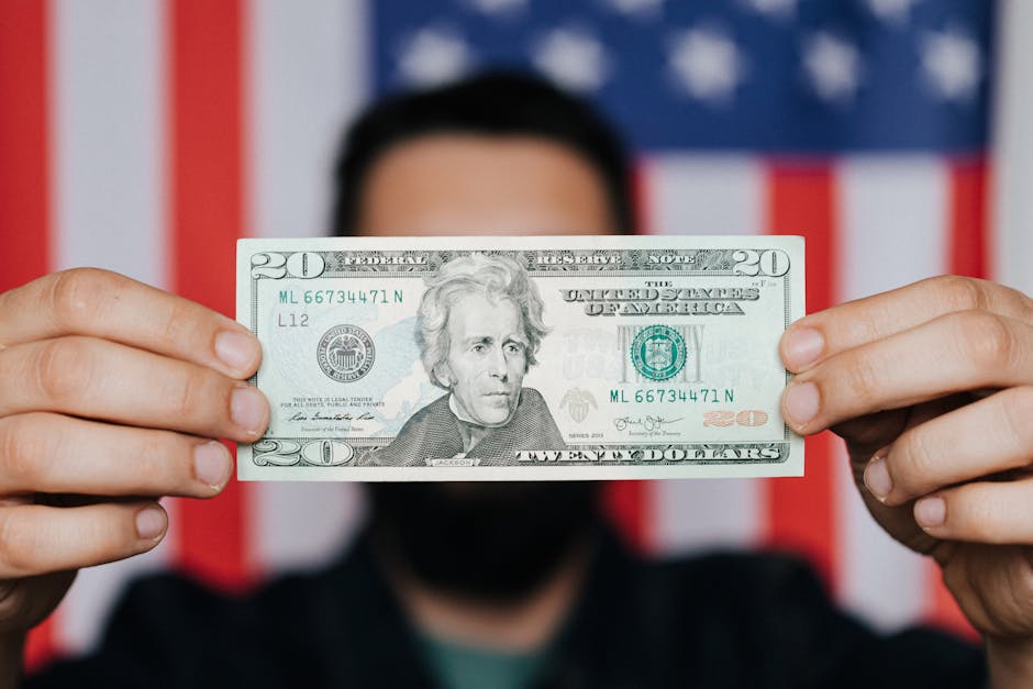Blurred adult man demonstrating United States paper bill for personal financial operations hiding face on background of USA national flag